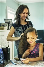 Smiling mother brushing hair of daughter