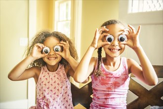 Mixed race sisters playing with googly eyes