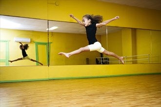 Mixed race girl leaping in ballet studio