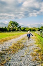 Caucasian girl walking on dirt road on ranch