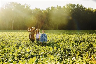 Caucasian family standing in crop field on farm