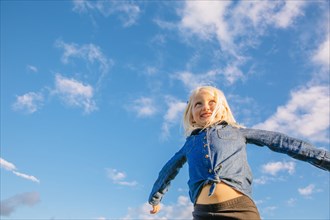 Low angle view of Caucasian girl standing under blue sky