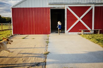 Caucasian girl running to barn on farm