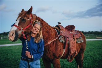 Caucasian woman smiling with horse on ranch