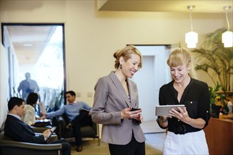 Businesswomen using digital tablet in office hallway
