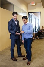 Businessmen using digital tablet in office hallway