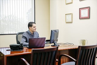 Mixed race businessman sitting in office