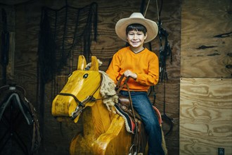 Caucasian boy riding toy wooden horse