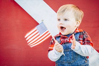 Caucasian boy waving American flag outside barn