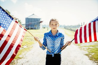 Caucasian girl waving American flags on farm