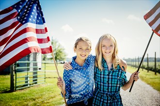 Caucasian girls waving American flags on farm