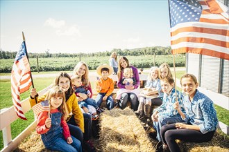 Caucasian family waving American flags on hay ride
