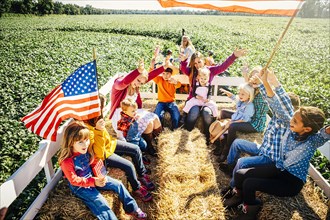 Caucasian family waving American flags on hay ride