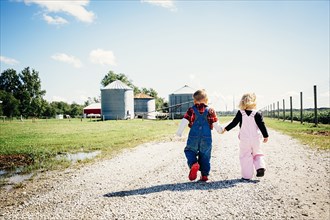 Caucasian brother and sister walking on farm