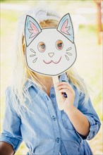 Caucasian girl holding cat mask