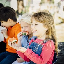 Caucasian children eating watermelon outdoors