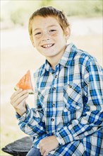 Caucasian boy eating watermelon outdoors