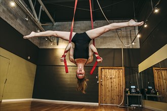 Caucasian acrobat hanging from ropes in studio