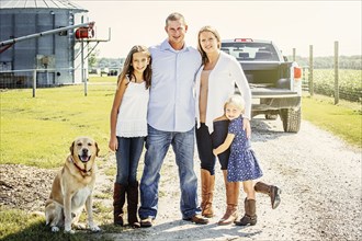 Caucasian family and dog standing on farm road