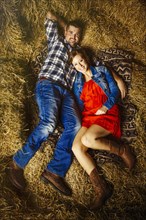 Caucasian couple laying on haystacks