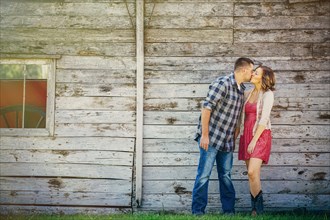 Caucasian couple kissing near wooden building