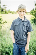Caucasian boy standing in tall grass field