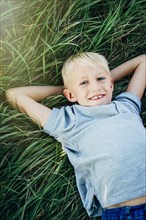 Caucasian boy laying in tall grass