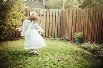 Mixed race girl wearing angel costume in backyard