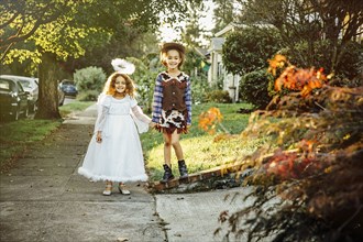 Sisters wearing Halloween costumes on sidewalk