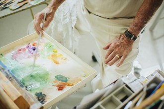 Caucasian artist mixing paint in palette in studio