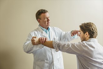 Caucasian doctor adjusting arm of patient