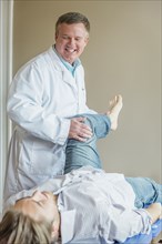 Caucasian doctor adjusting leg of patient