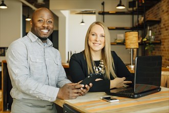 Waiter and businesswoman using technology in cafe