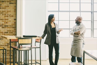 Black businesswoman and waiter talking in cafe