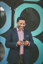 Mixed race businessman using cell phone outdoors