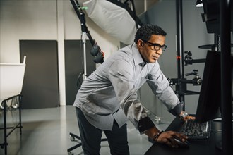 Mixed race photographer using computer in studio