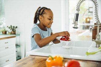 Black girl washing strawberries in kitchen