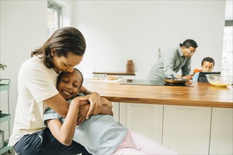 Mother hugging daughter in kitchen