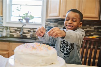 Black boy decorating cake in kitchen