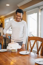 Black woman lighting candles on birthday cake