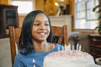 Black girl blowing out candles on birthday cake