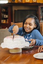 Black girl cutting cake at birthday party
