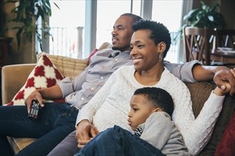 Black family watching television on sofa