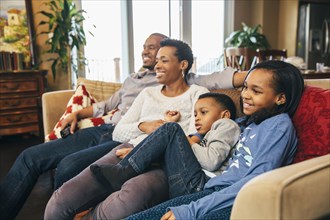 Black family watching television on sofa