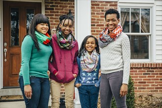 Black mother and daughters smiling outside house
