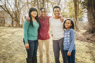 Black mother and daughters smiling outdoors