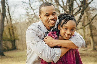 Black father and daughter hugging outdoors