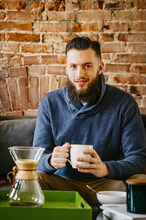 Man drinking coffee on sofa in living room