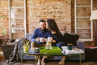 Couple drinking coffee on sofa in living room