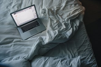 Laptop on empty bed